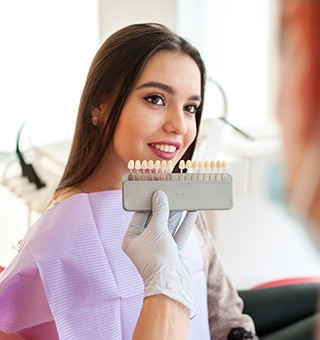 Dentist comparing shade of woman's teeth