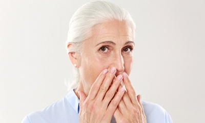 older woman covering mouth in shame