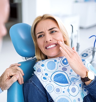 Woman in dental chair holding cheek