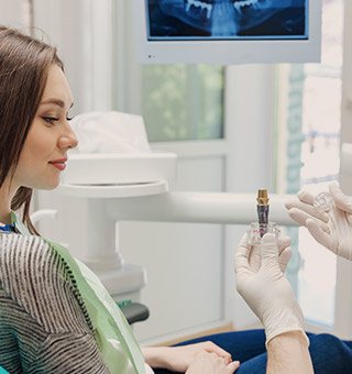 Dentist showing patient dental implant model