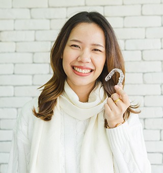 woman smiling holding Invisalign